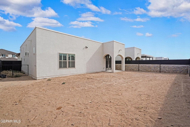 back of property featuring fence and stucco siding