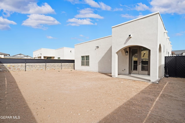 back of property featuring french doors, a patio area, fence, and stucco siding