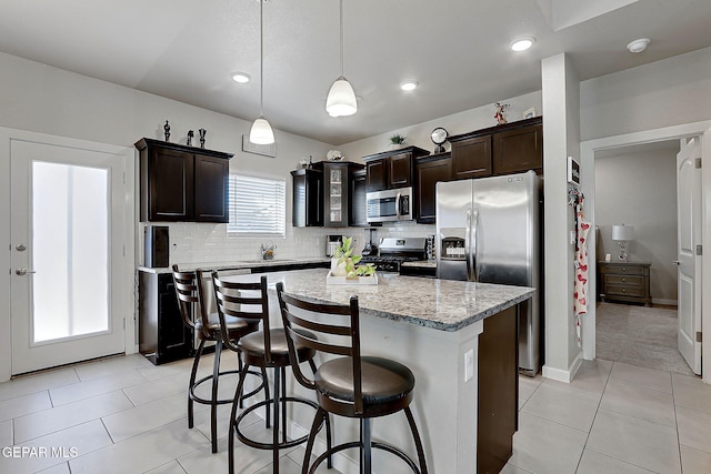 kitchen with dark brown cabinetry, hanging light fixtures, stainless steel appliances, and a center island