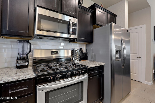 kitchen featuring light stone counters, appliances with stainless steel finishes, light tile patterned flooring, and decorative backsplash