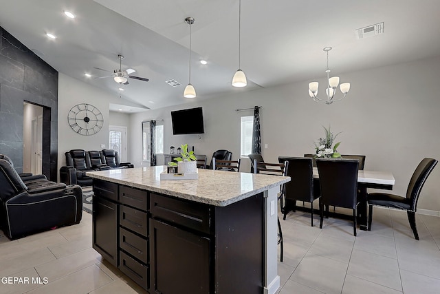 kitchen featuring light tile patterned flooring, decorative light fixtures, a center island, vaulted ceiling, and ceiling fan with notable chandelier