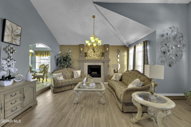 living room featuring a tile fireplace, vaulted ceiling, a chandelier, and light wood-type flooring