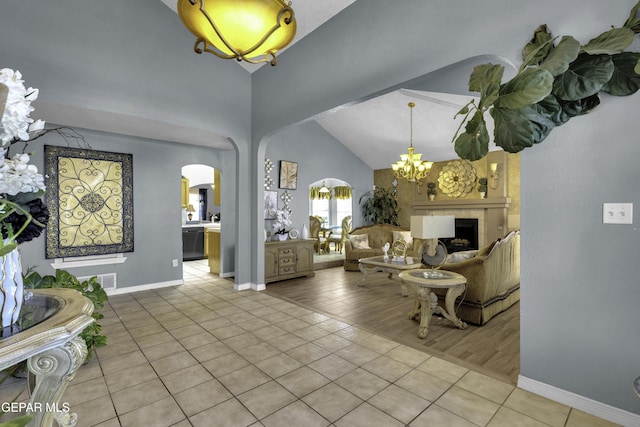 living room with an inviting chandelier, high vaulted ceiling, and light tile patterned flooring