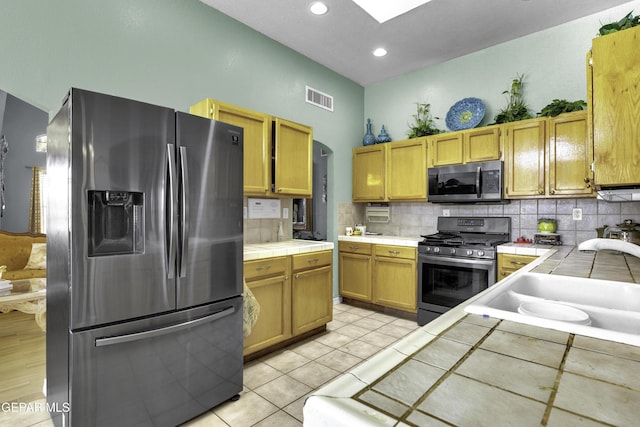 kitchen featuring appliances with stainless steel finishes, sink, tile counters, and backsplash