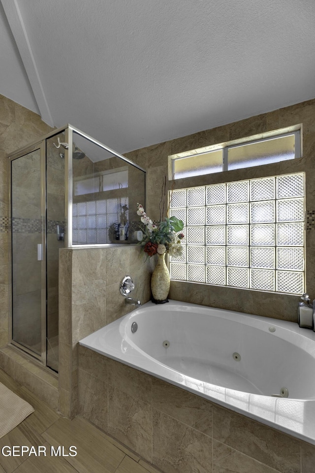 bathroom featuring independent shower and bath, a textured ceiling, and a wealth of natural light