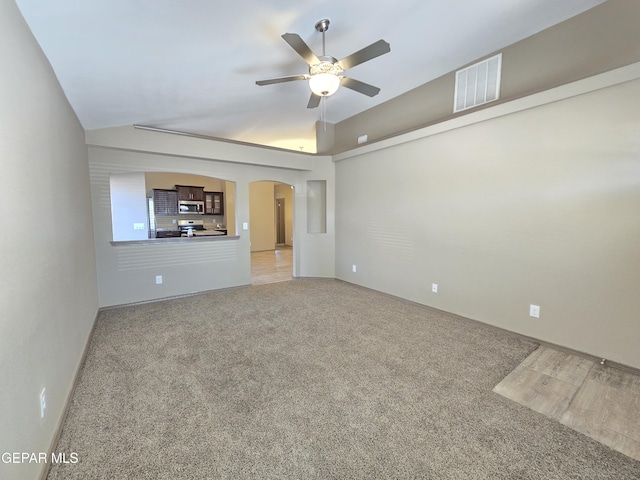 unfurnished living room featuring vaulted ceiling, ceiling fan, and carpet