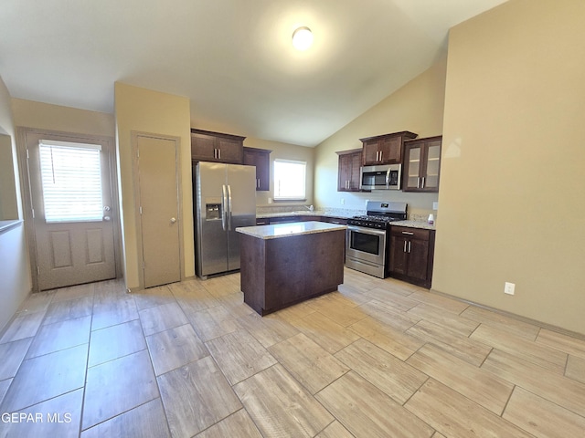 kitchen featuring appliances with stainless steel finishes, a center island, lofted ceiling, and dark brown cabinets