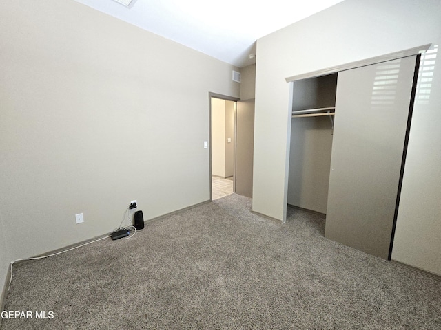 unfurnished bedroom with light colored carpet and a closet