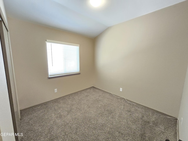 carpeted spare room with lofted ceiling