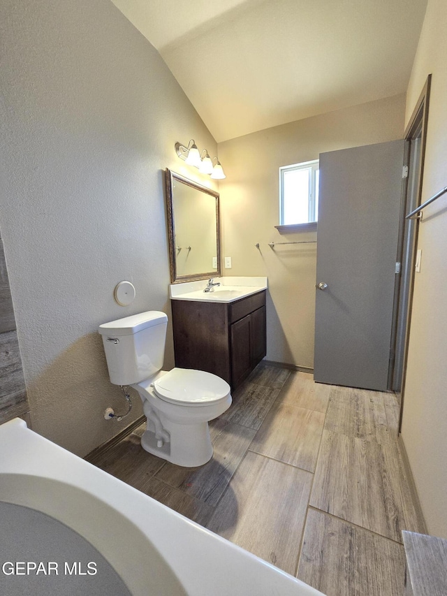 bathroom featuring vaulted ceiling, hardwood / wood-style floors, vanity, and toilet