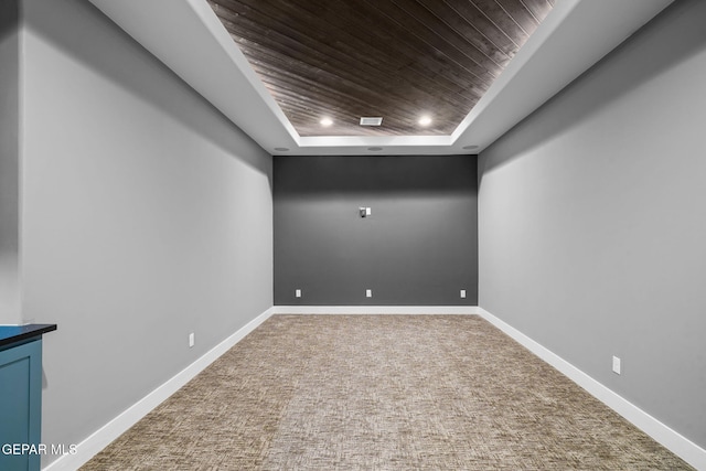 carpeted empty room with a tray ceiling and wooden ceiling