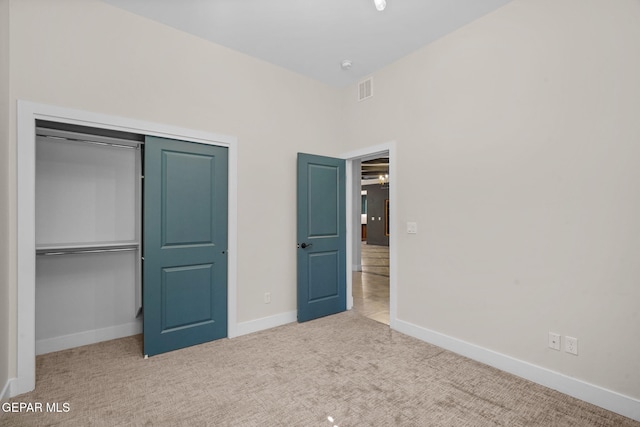 unfurnished bedroom with light colored carpet and a closet