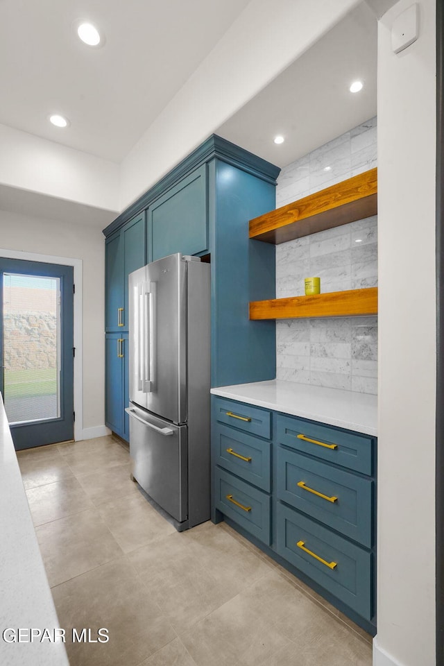 kitchen featuring stainless steel refrigerator, blue cabinets, and tasteful backsplash