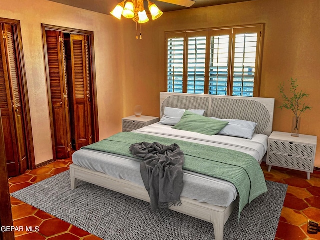 bedroom featuring tile patterned flooring, two closets, and ceiling fan