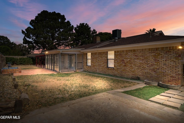 11204 Bob Mitchell Dr, El Paso, TX 79936 - back of house featuring a patio, a sunroom, a yard, a chimney, and brick siding