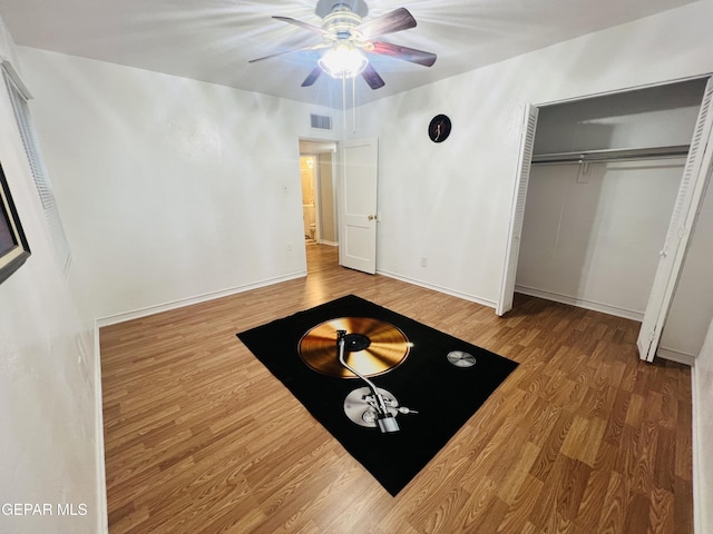 unfurnished bedroom featuring wood-type flooring, ceiling fan, and a closet