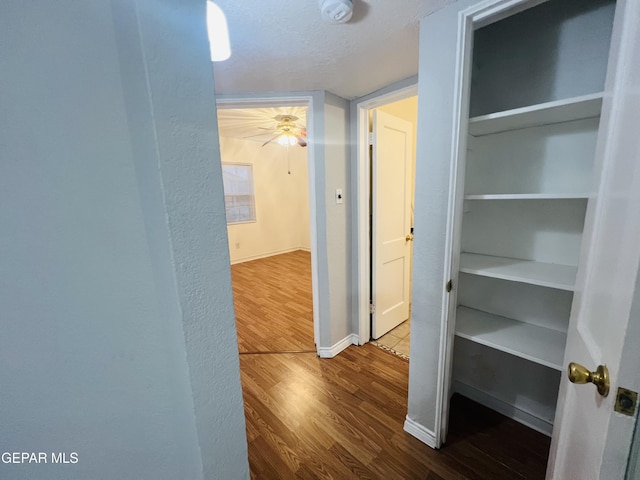 corridor with hardwood / wood-style floors and a textured ceiling