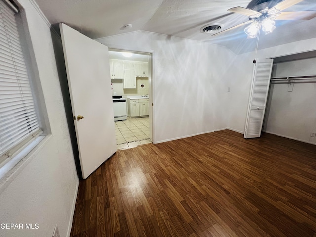 unfurnished bedroom with ceiling fan, lofted ceiling, wood-type flooring, and a closet