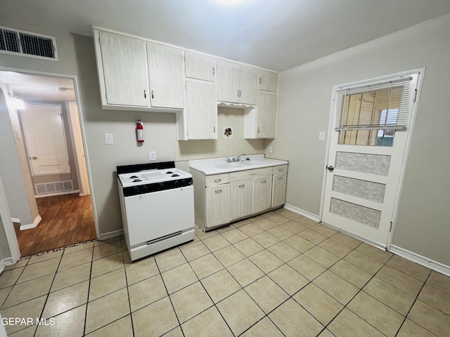 kitchen featuring decorative backsplash, sink, gas range gas stove, and light tile patterned floors