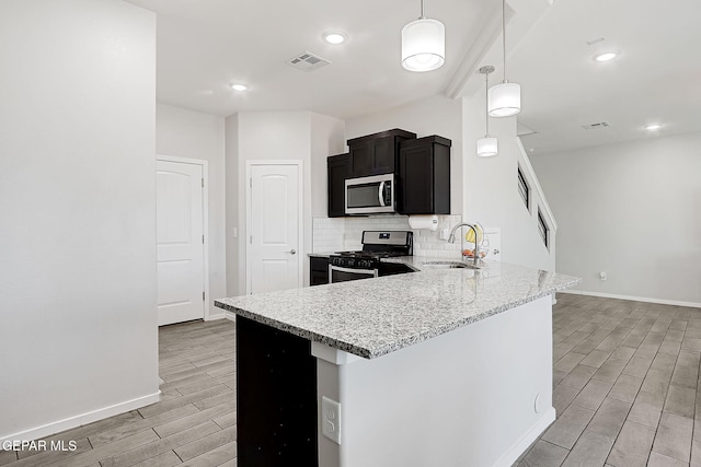 kitchen with tasteful backsplash, sink, hanging light fixtures, stainless steel appliances, and light stone countertops