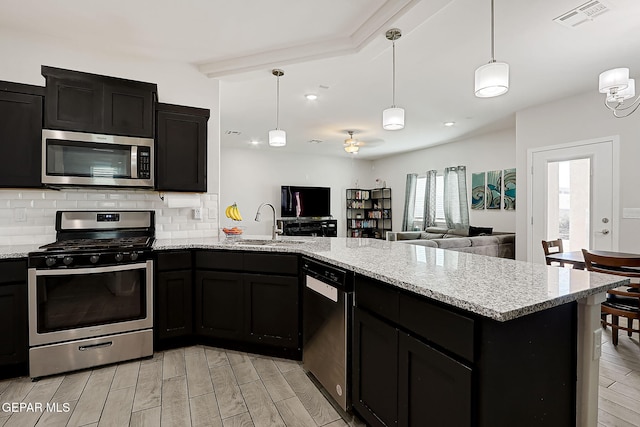 kitchen with decorative light fixtures, tasteful backsplash, sink, kitchen peninsula, and stainless steel appliances