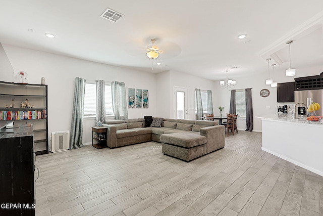 living room featuring ceiling fan with notable chandelier and light wood-type flooring