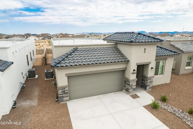 view of front facade with a garage, a mountain view, and central air condition unit