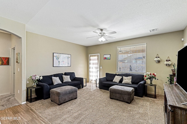 living area with ceiling fan, visible vents, arched walkways, and a textured ceiling