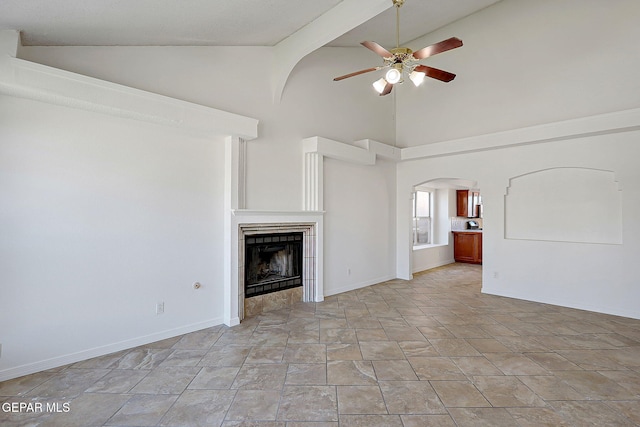 unfurnished living room with a tile fireplace, lofted ceiling, and ceiling fan