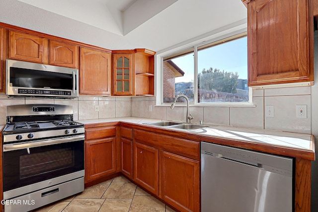 kitchen with stainless steel appliances, tile countertops, sink, and decorative backsplash