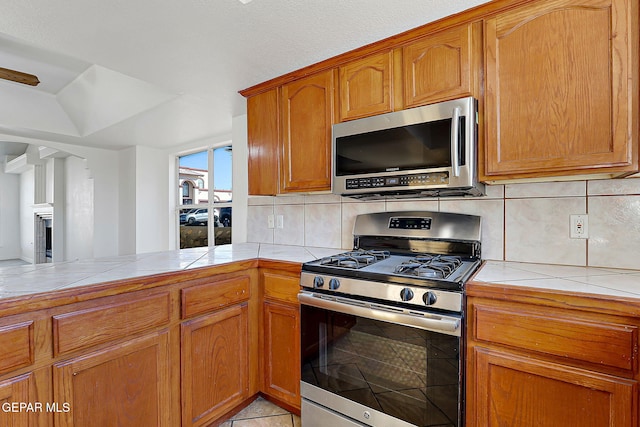 kitchen with stainless steel appliances, tasteful backsplash, tile countertops, and kitchen peninsula