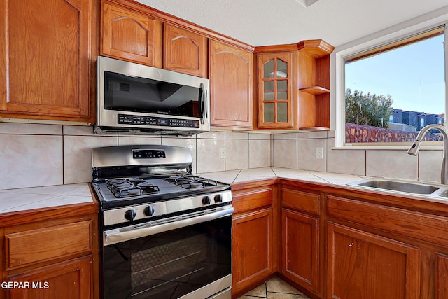 kitchen featuring appliances with stainless steel finishes, tile countertops, sink, and decorative backsplash