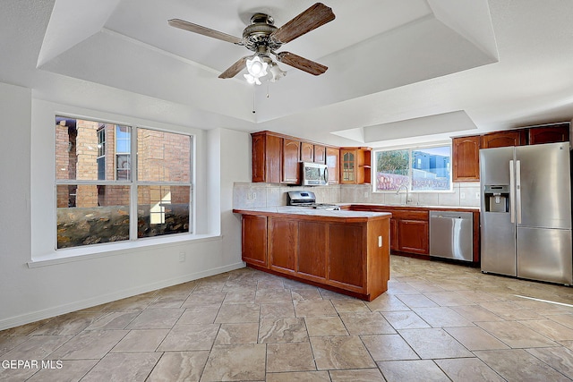 kitchen with sink, a tray ceiling, stainless steel appliances, and kitchen peninsula