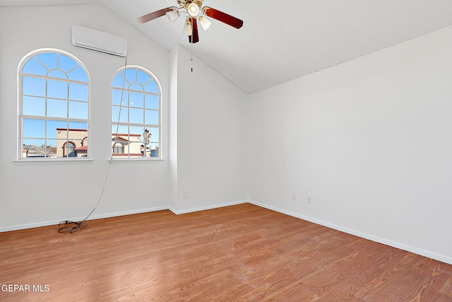 additional living space featuring ceiling fan, vaulted ceiling, a wall unit AC, and light hardwood / wood-style flooring