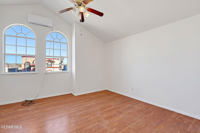 spare room featuring ceiling fan, lofted ceiling, a wall mounted AC, and light hardwood / wood-style flooring