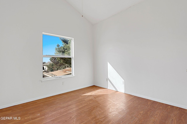 spare room featuring hardwood / wood-style floors and high vaulted ceiling