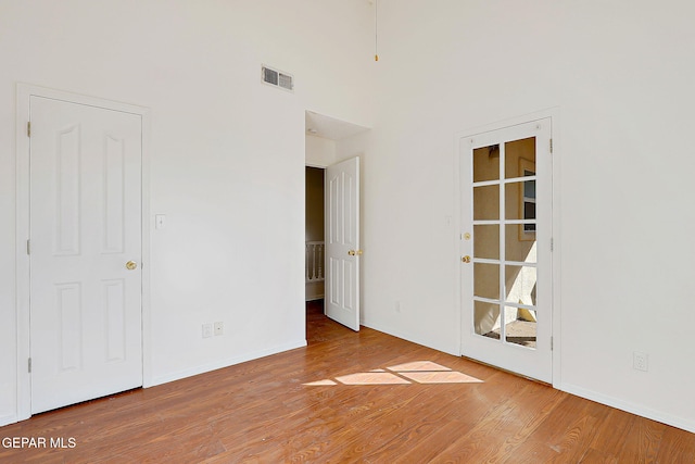 empty room with hardwood / wood-style flooring and a high ceiling