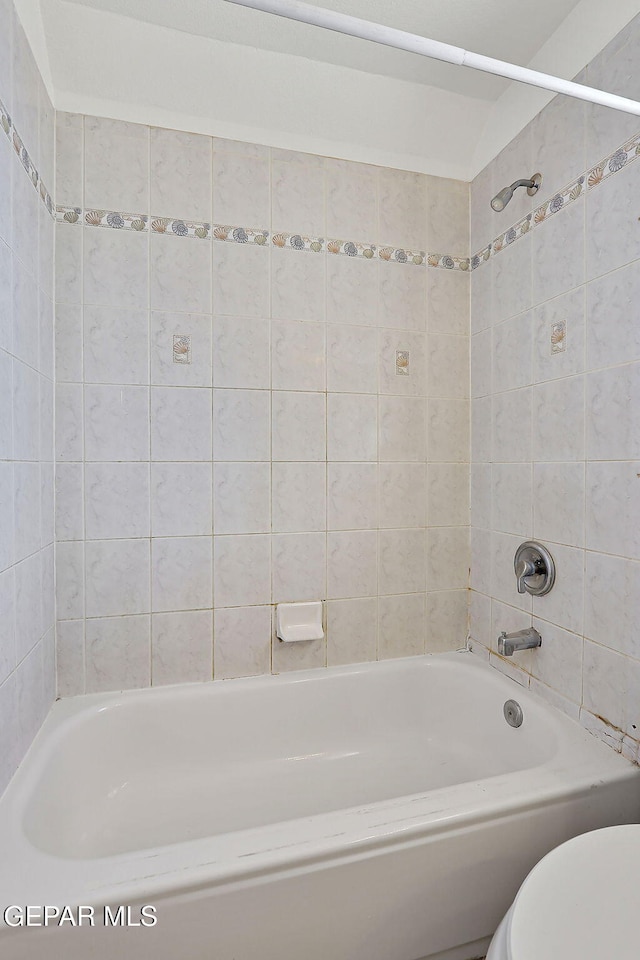 bathroom with tiled shower / bath combo and toilet