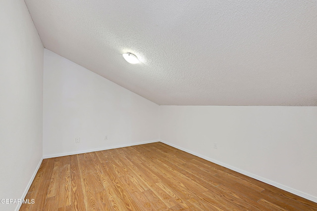 bonus room with vaulted ceiling, a textured ceiling, and light hardwood / wood-style floors