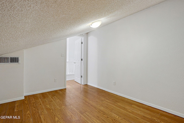 bonus room with a textured ceiling and light hardwood / wood-style floors