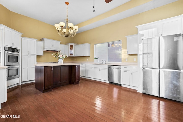 kitchen with dark hardwood / wood-style floors, pendant lighting, white cabinetry, sink, and stainless steel appliances