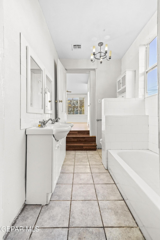 bathroom with vanity, a notable chandelier, a bathtub, and tile patterned floors