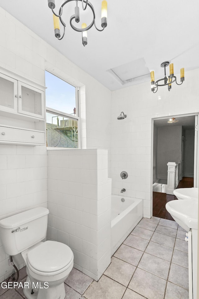 bathroom featuring tile patterned flooring, tile walls, an inviting chandelier, and toilet