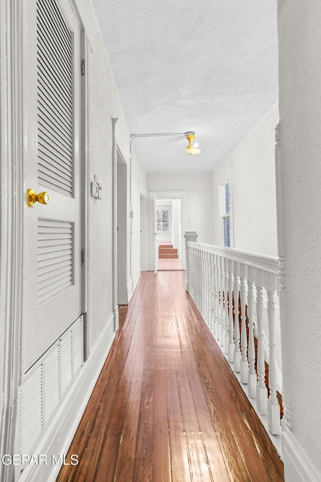 hallway with hardwood / wood-style flooring and a textured ceiling