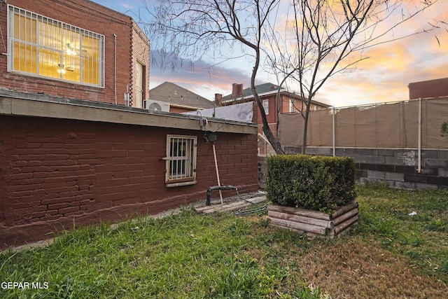 property exterior at dusk featuring a lawn