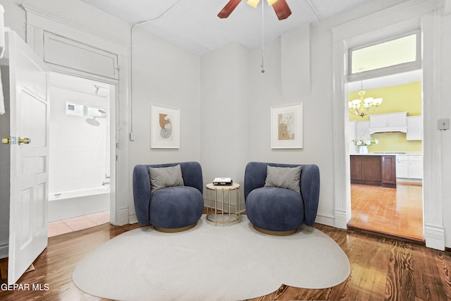 living area featuring hardwood / wood-style floors and ceiling fan with notable chandelier