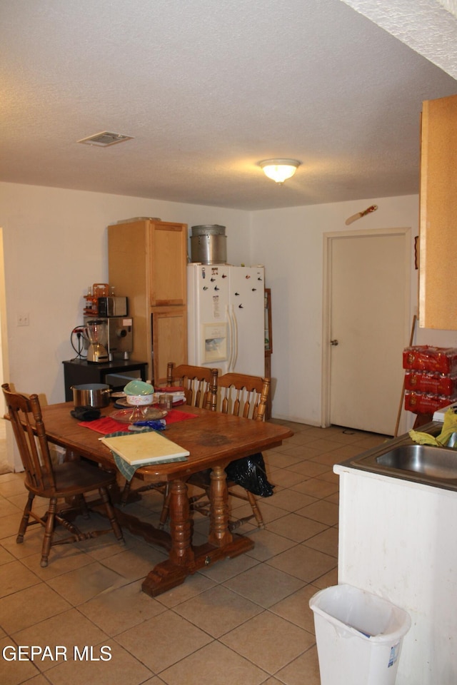 dining area with sink, light tile patterned floors, and a textured ceiling