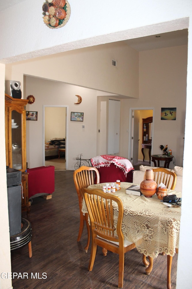 dining area with dark hardwood / wood-style floors and high vaulted ceiling