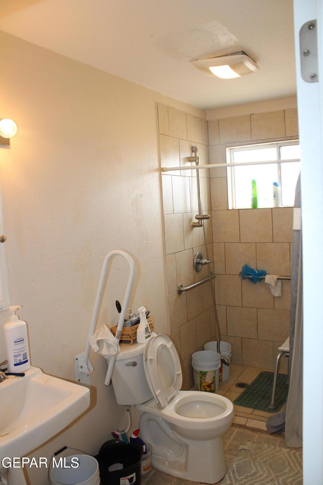 bathroom with sink, toilet, and tiled shower