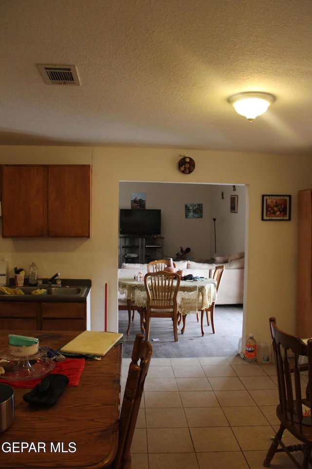 tiled dining space with sink and a textured ceiling